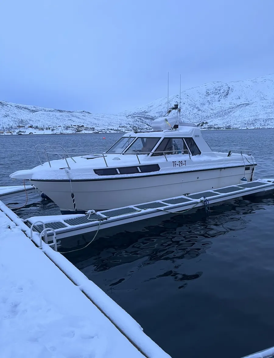 Båt til fisketur ved kai i snødekt fjord