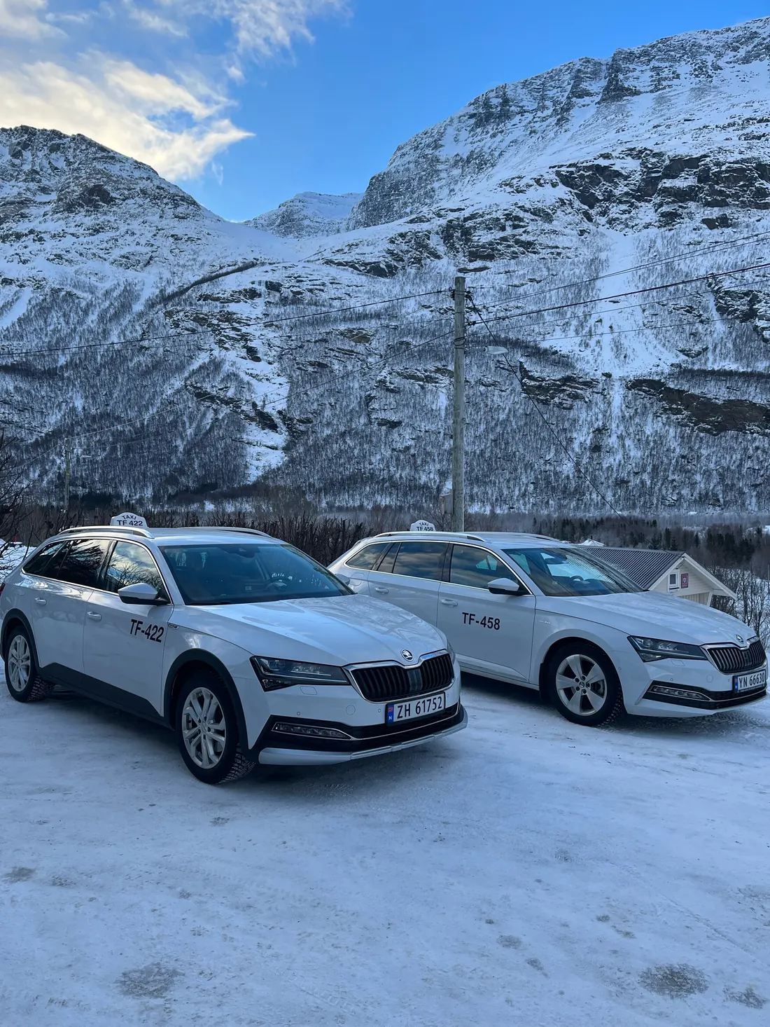 To hvite taxier foran snødekte fjell i Birtavarre